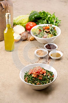 Plates of traditional Arabic salad fattouch and tabbouleh on a rustic background