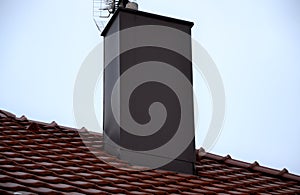 Plating the chimney on the roof of burnt tiles. chimney protection against rain, frost and snow with a brown plate. The tinsmith c