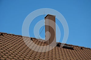 Plating the chimney on the roof of burnt tiles. chimney protection against rain, frost and snow with a brown plate. The tinsmith c