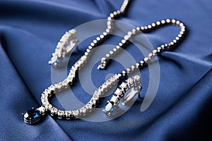 Platinum necklace and earrings with a diamond and blue precious