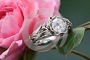 platinum wedding rings on a budding peony, with natural background