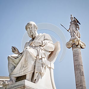 Plato, the philosopher and Athena, goddess of knowledge and wisdom, white marble statues under clear blue sky.