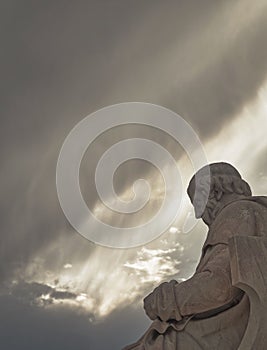 Plato's marble statue, the ancient Greek philosopher in deep thoughts, under an impressive cloudy sky with sun patches. photo