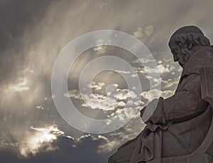 Plato marble statue, the ancient Greek philosopher in deep thoughts, under an impressive cloudy sky with sun patches. photo