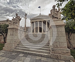 Plato and Socrates statues in front of the national academy of Athens, Greece under impressive cloudy sky