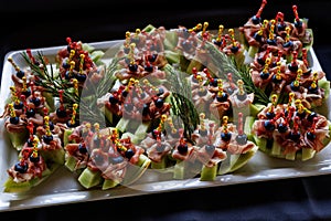 A platter of appetizing hors d oeuvres with colorful skewers on a black background photo