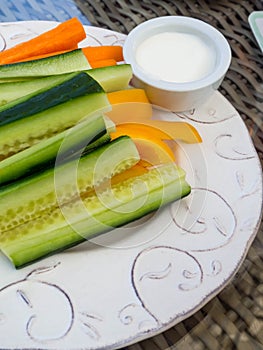 Platter of assorted fresh vegetables with yogurt dip on white plate