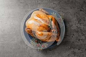 Platter of cooked turkey with cranberry and fir tree branches on grey background