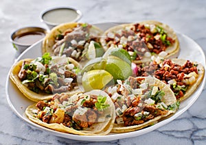 Platter of mexican street tacos with carne asada, chorizo, and al pastor in corn tortillas