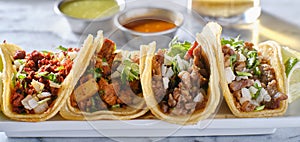 Platter of mexican street tacos with carne asada, chorizo, and al pastor in corn tortillas photo