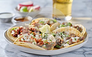 Platter of mexican street tacos with carne asada, chorizo, and al pastor in corn tortillas