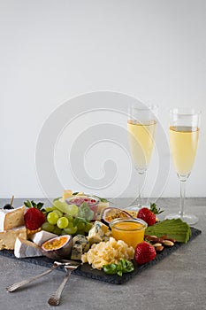 Platter with organic cheeses, fruits, berries and wine on a gray background. Delicious cheese appetizer.