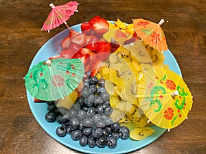 Platter of seasonal summer fruit  with whimsical drink umbrellas