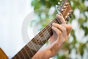 Play acoustic guitar closeup. Guitar fretboard with male hand