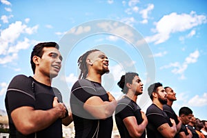 Play with all your heart. a team of young rugby players singing the national anthem before a game.