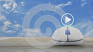 Play button with wireless computer mouse on wooden table over blue sky with white clouds, Business music online concept