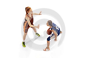 Play defense. Two basketball players, young girls, teen training with basketball ball isolated on white background