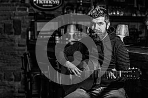 Play the guitar. Beard hipster man sitting in a pub. Music concept. Bearded guitarist plays. Black and white