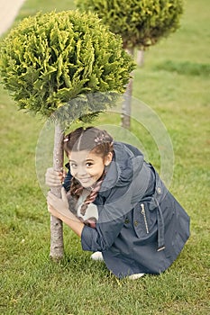 Play hide and seek. Girl cute kid green grass background. Healthy emotional happy kid relaxing outdoors. What makes