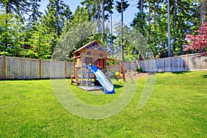 Play kids ground area with chute in fenced backyard.