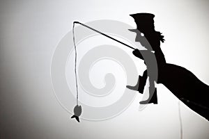 Play shadow projected against a white background. a homeless man with a rod fishing