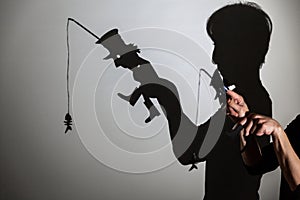 Play shadow projected against a white background. a homeless man with a rod fishing