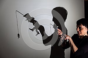 Play shadow projected against a white background. a homeless man with a rod fishing