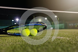 Play tennis in dark with artificial lighting. racket and balls on outdoor court. copy space