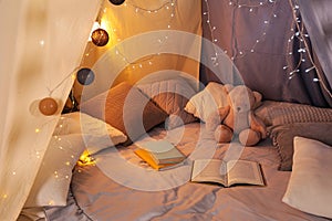 Play tent with books, pillows and Teddy bear. Modern children`s room interior