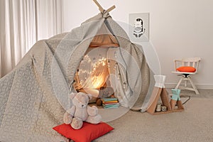 Play tent decorated with festive lights in modern child`s room