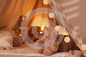 Play tent with toys and pillows indoors, closeup. Modern children`s room interior