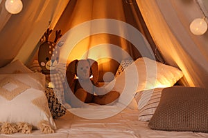 Play tent with toys and pillows indoors, closeup. Modern children`s room interior