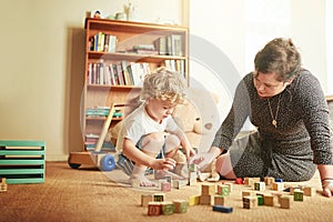 Play is a vital way of learning. Shot of a mother and her little son playing with wooden blocks at home.