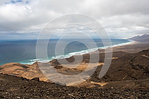 Playa De Cofete Canary Islands, Fuerteventura, Spain. Beach, mountains and Atlantic Ocean against cloudy sky
