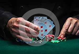 A player bets on a winning combination of four of a kind or quads in a game of poker on a green table with chips in a club