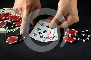 The player bets on a winning combination of three of a kind or a set in a poker game on a black table with chips and money in a