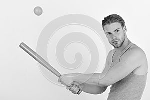 Player with concentrated face plays baseball. Guy in grey tank top holds bright green bat about to hit orange ball