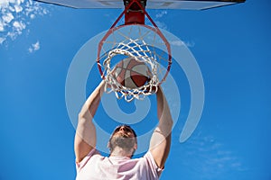 player dunking basketball ball through net ring with hands, sport motivation