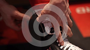 A player in hockey ties laces on skates before the game. Action. Close up of male hands prepares himself for a hockey