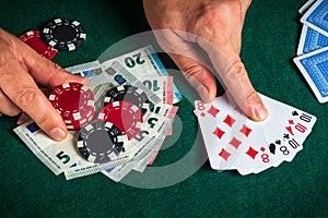 Player points with his finger at a winning full house or full boat combination in poker game on a table with chips and money in a