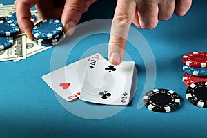 The player points with his finger at a winning one pair combination in poker game on a blue table with chips and money in club