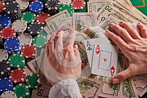A player in a poker casino put a pair of aces on the background of chips and money of dollars. Victory, success. Gaming business
