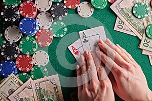 A player in a poker casino shows a pair of aces against the background of chips and money of dollars. Victory, success. Gaming