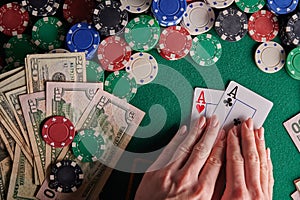 A player in a poker casino shows a pair of aces against the background of chips and money of dollars. Victory, success. Gaming