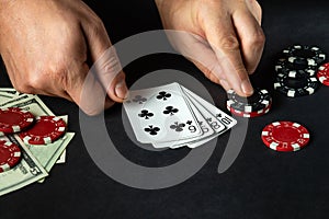 Player puts playing cards with straight flush winning combination in poker game on black table with chips and money in club