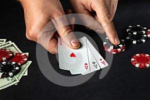 The player puts playing cards with a winning combination of three of a kind or set in game of poker on a black table with chips