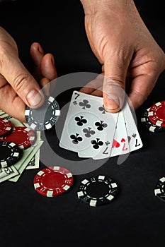 The player puts playing cards with a winning combination of three of a kind or set in a game of poker on a black table with chips