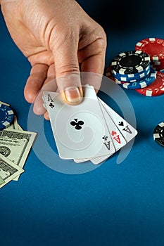 The player puts playing cards with a winning combination of three of a kind or set in a game of poker on a blue table with chips