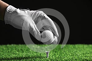 Player putting golf ball on tee against black , closeup