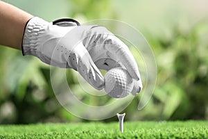 Player putting golf ball on tee against blurred background